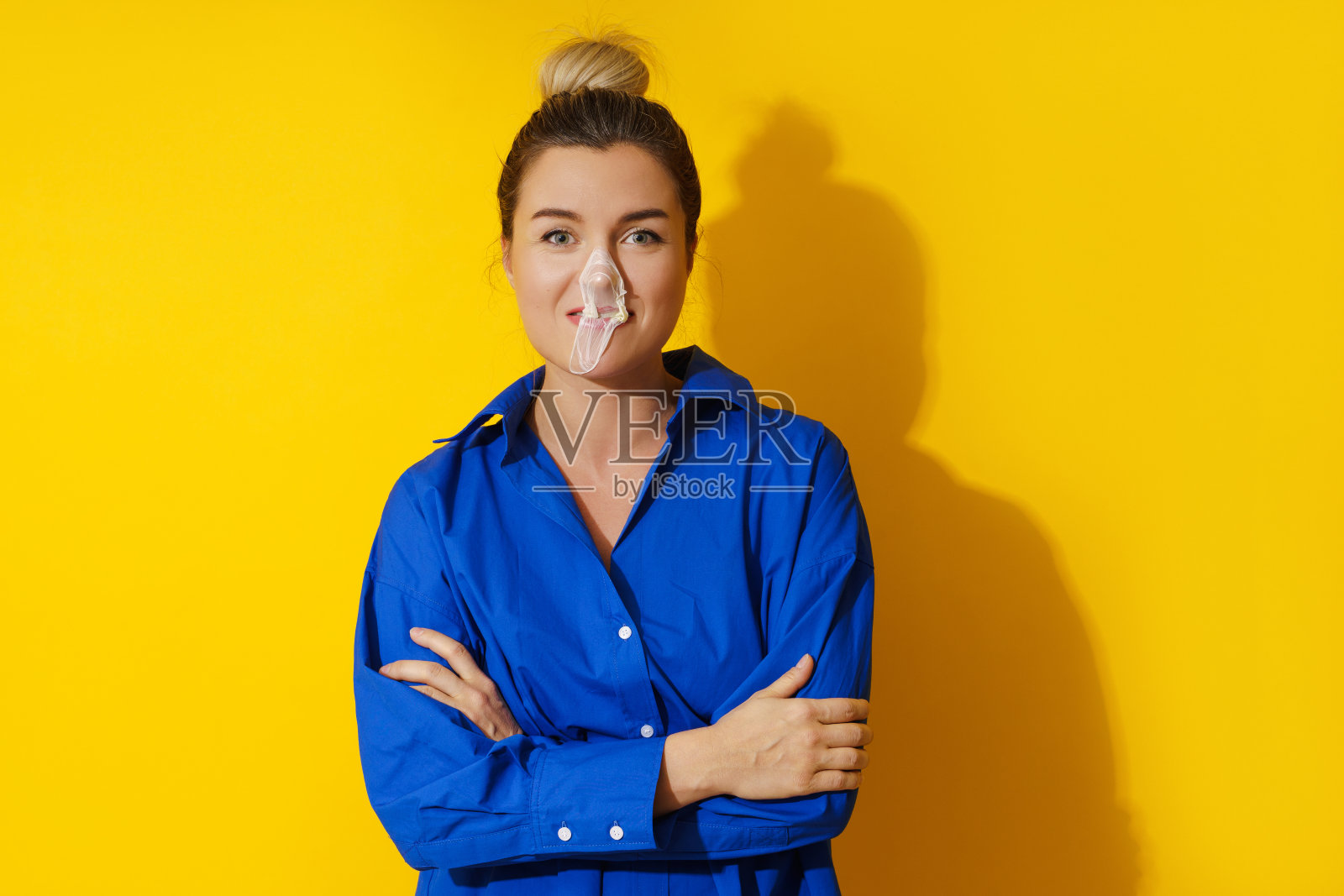 快乐的女人在黄色的背景下用口香糖吹泡泡照片摄影图片