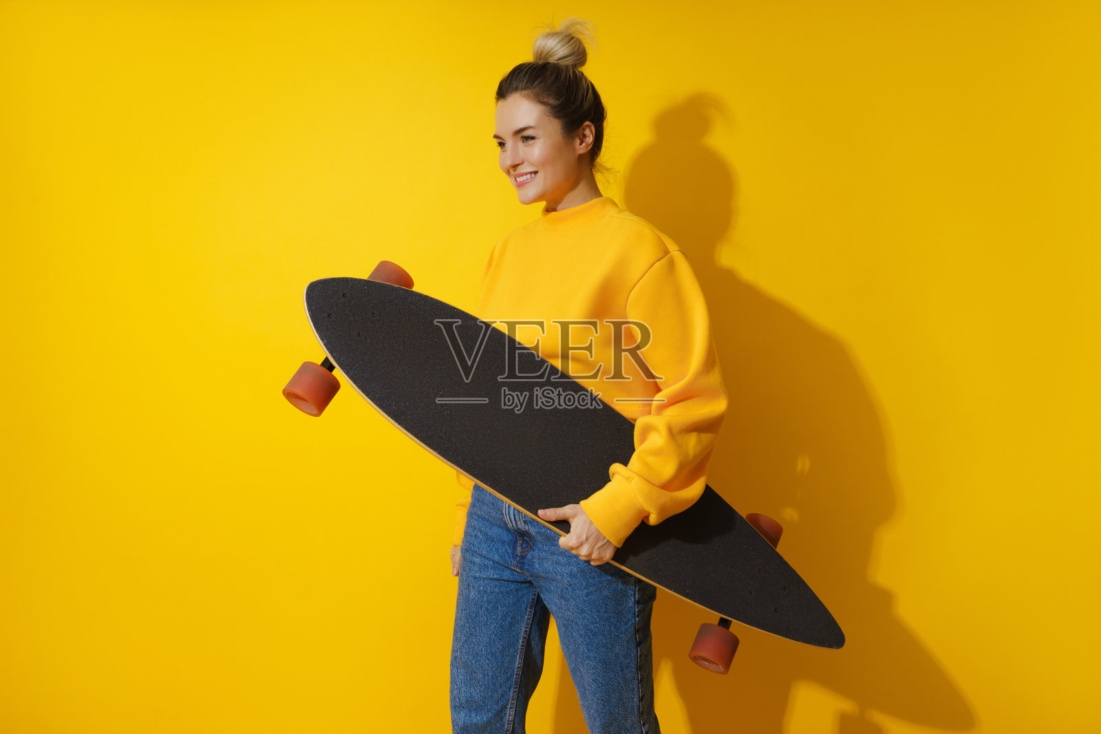 年轻开朗的女孩与长板对黄色背景照片摄影图片