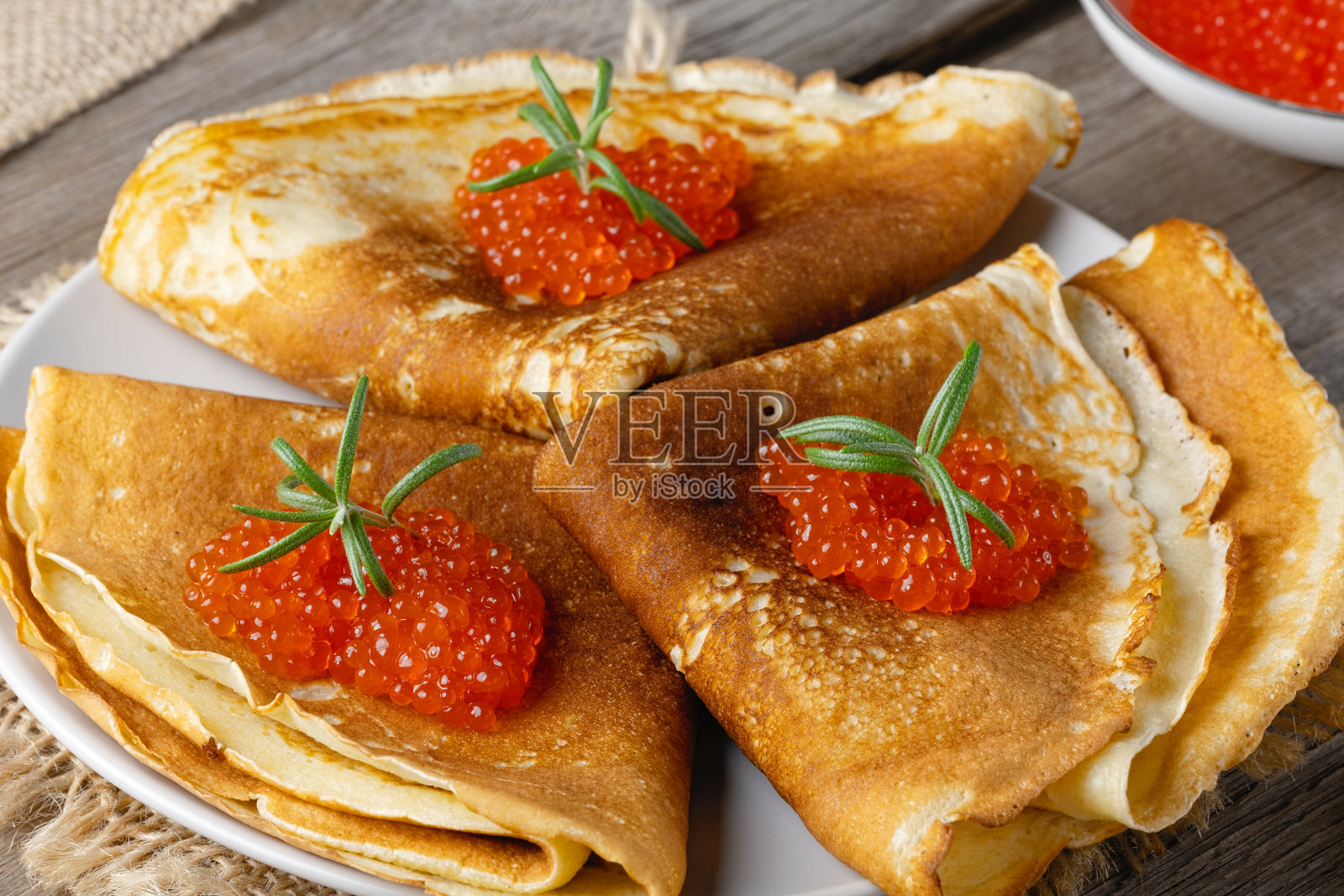 旧木桌上放着一叠俄罗斯薄煎饼和红色鱼子酱。Maslenitsa，传统的俄罗斯blini照片摄影图片