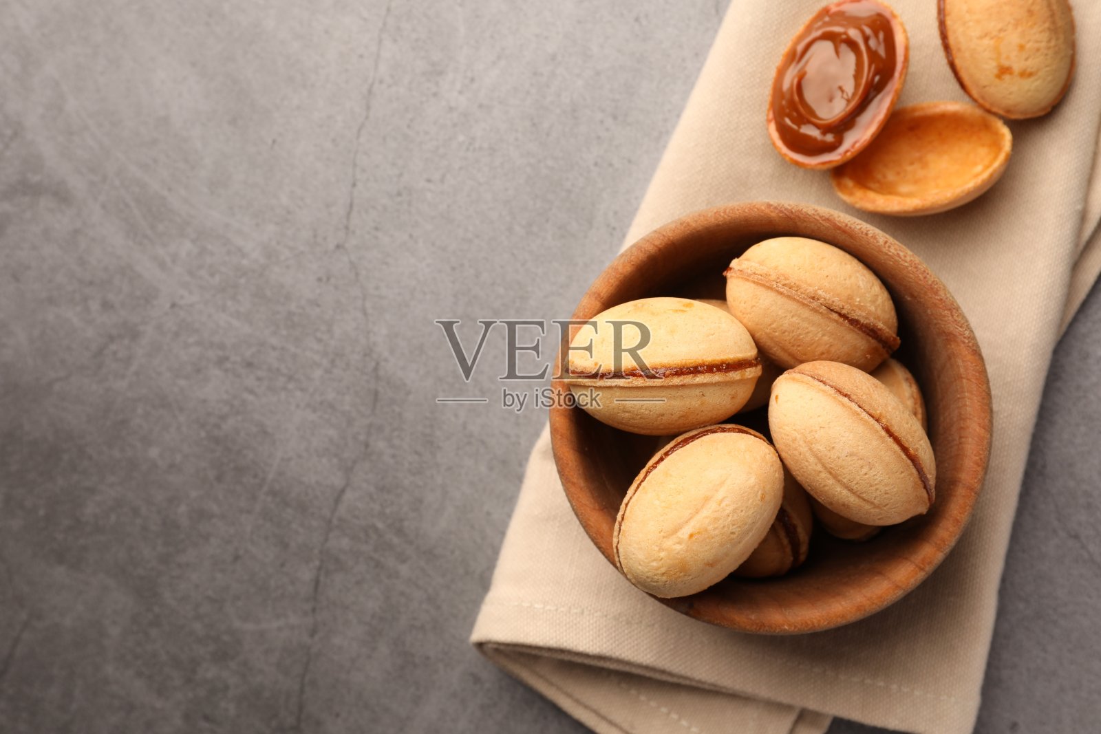美味的坚果形状的饼干和煮炼乳放在灰色纹理的桌子上，平铺。文本空间照片摄影图片