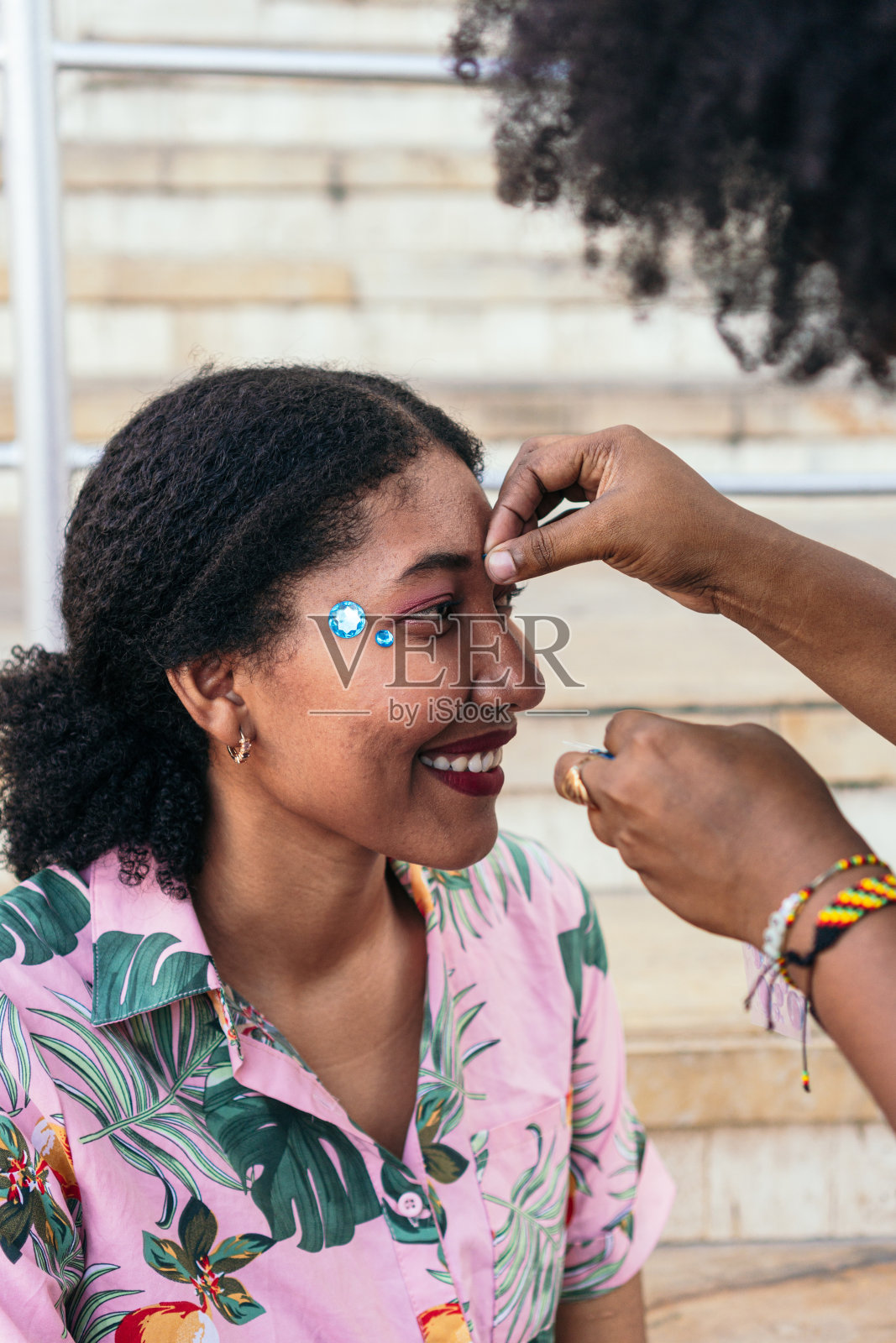 狂欢节期间，一名西班牙女子正在给她的朋友脸上涂亮片照片摄影图片