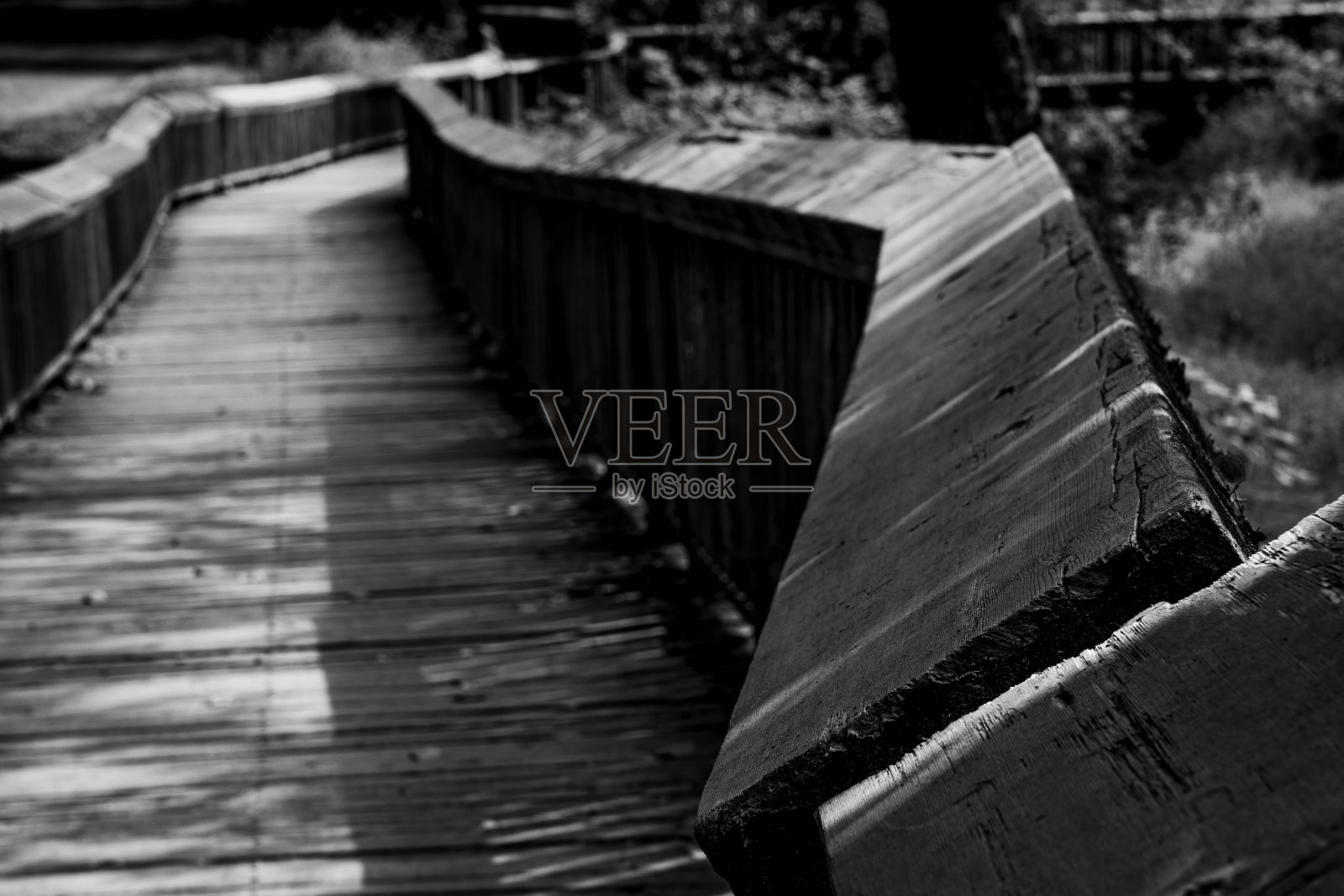 公园里的木制人行道在阳光下的灰度镜头，背景模糊照片摄影图片