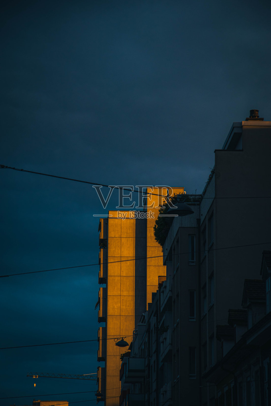 垂直拍摄的公寓大楼在黑暗多云的天空下，在晚上照片摄影图片