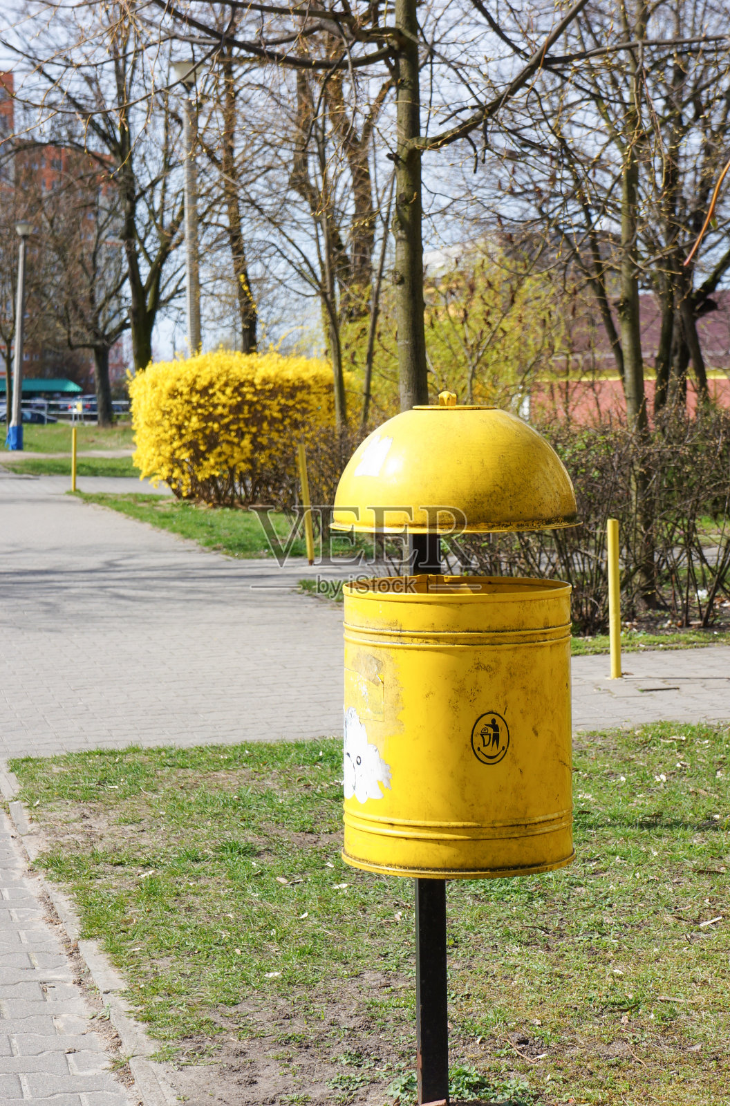 垂直拍摄一个黄色垃圾桶在一个公园的钢柱子上照片摄影图片