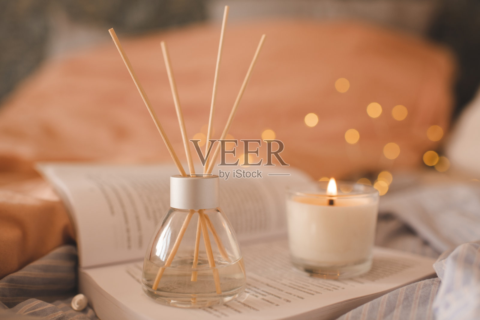 带香味的家用液体扩散器，用蜡烛和打开的书放在卧室里照片摄影图片