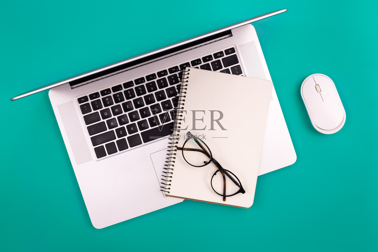 笔记本电脑和空白记事本在绿色背景，俯视图，复制空间。照片摄影图片