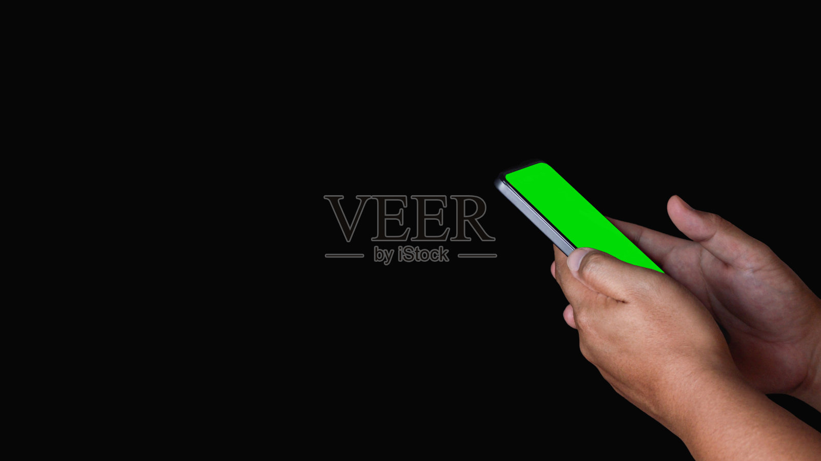 这个男人拿着一部智能手机。手机上的绿色屏幕。孤立在黑色背景上。照片摄影图片