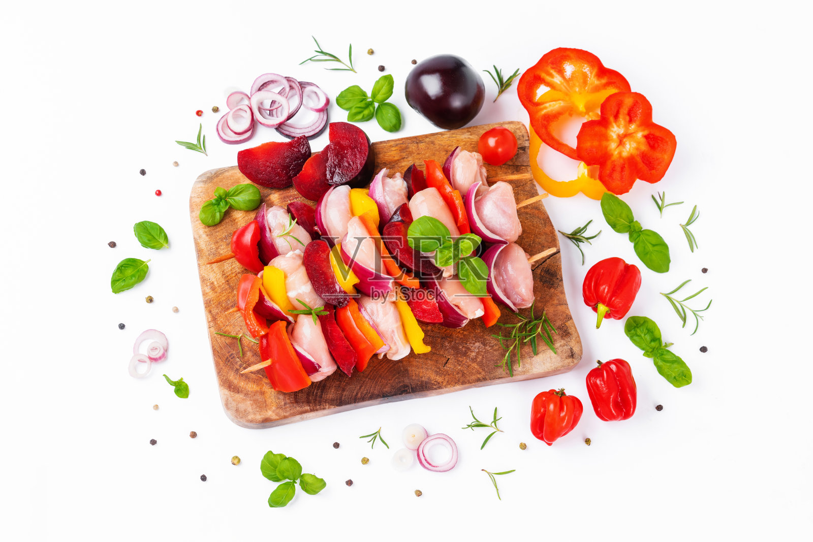 生鸡腿肉串，配上蔬菜，李子，辣椒，洋葱，白色背景。生椒杂肉串。串上生肉，红辣椒，黄辣椒和青椒。前视图。照片摄影图片