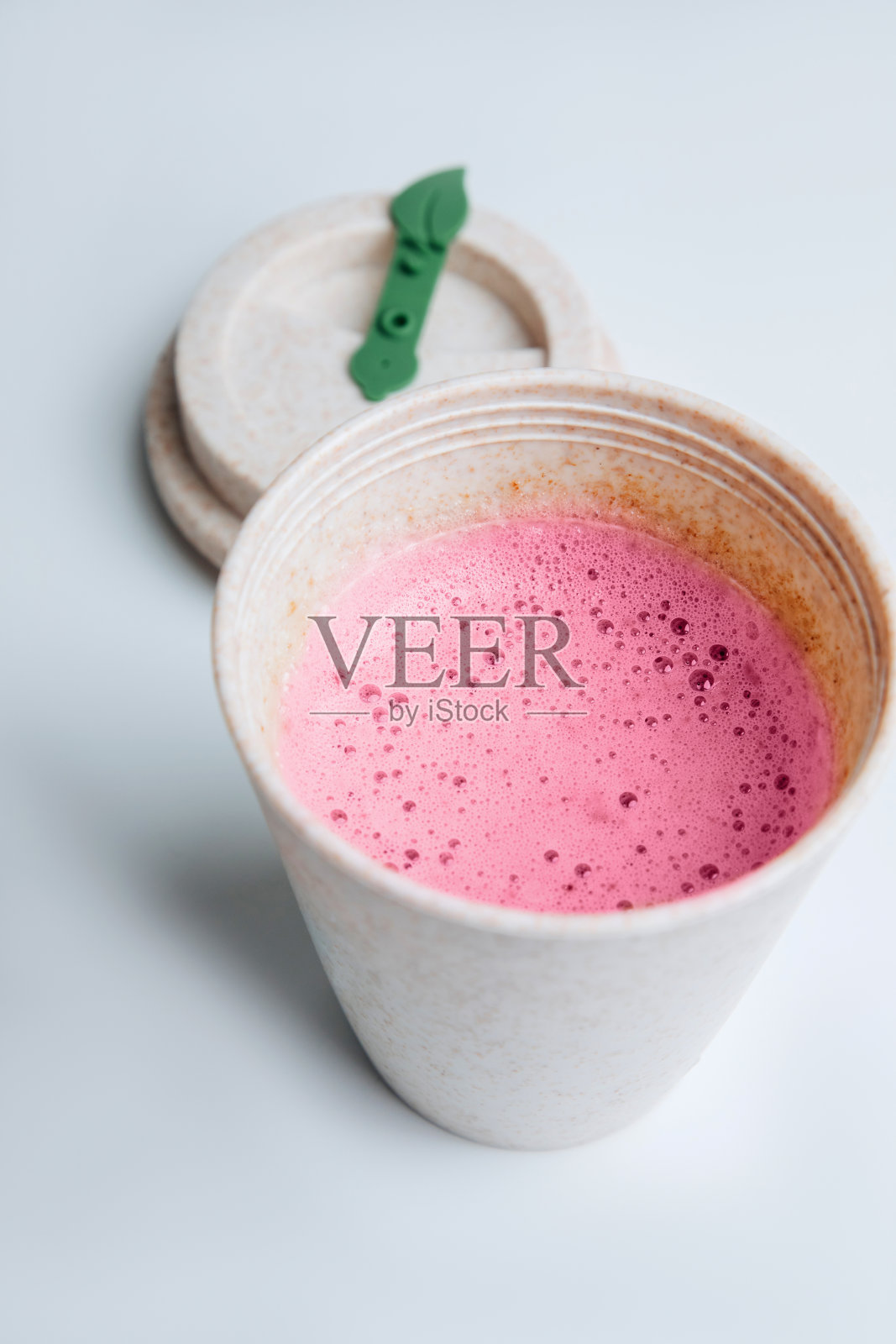 白色的桌子上，用生态杯盛着洋红色泡沫的咖啡照片摄影图片