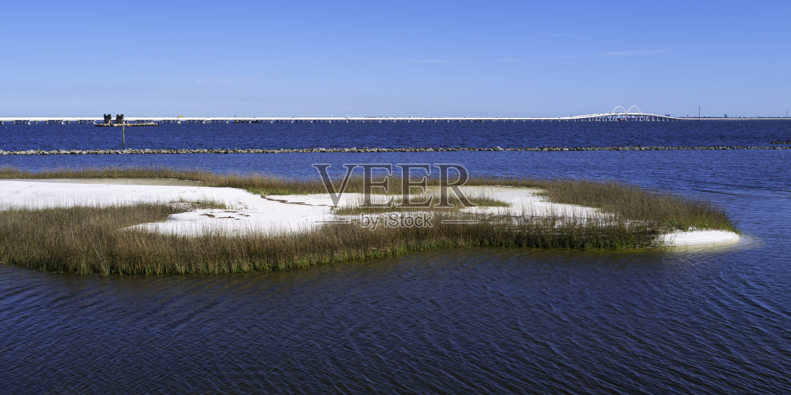 彭萨科拉湾宁静的海景，明亮的白色沙丘岛和蓝色的地平线上的桥在美国佛罗里达州照片摄影图片