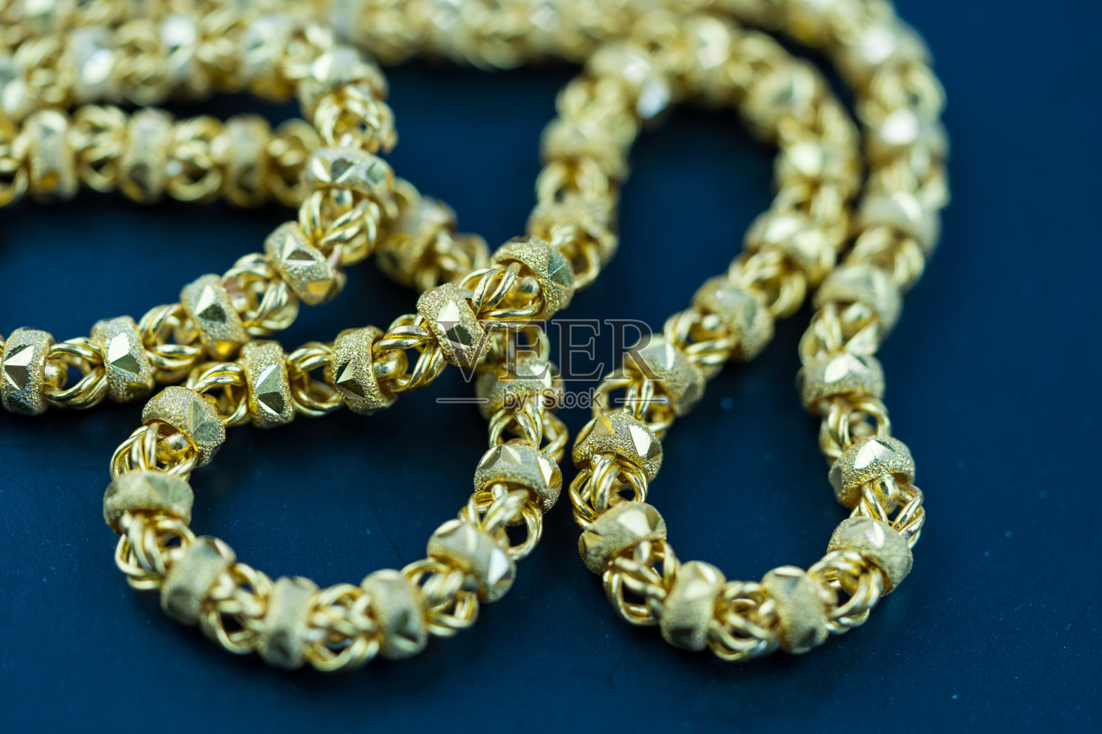 深蓝色背景的金链项链。照片摄影图片