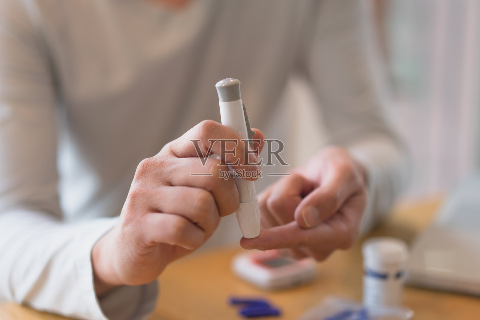 年轻男子在家里做健康检查时使用血液检测试剂盒。家庭手指刺血测试。近距离、糖尿病概念、老年保健、照片摄影图片