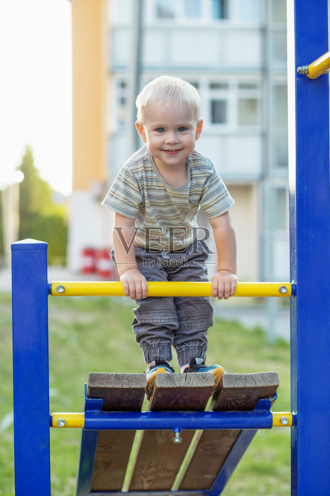 小男孩在操场上爬。可爱的微笑的孩子在户外玩耍。幼儿园的概念照片摄影图片