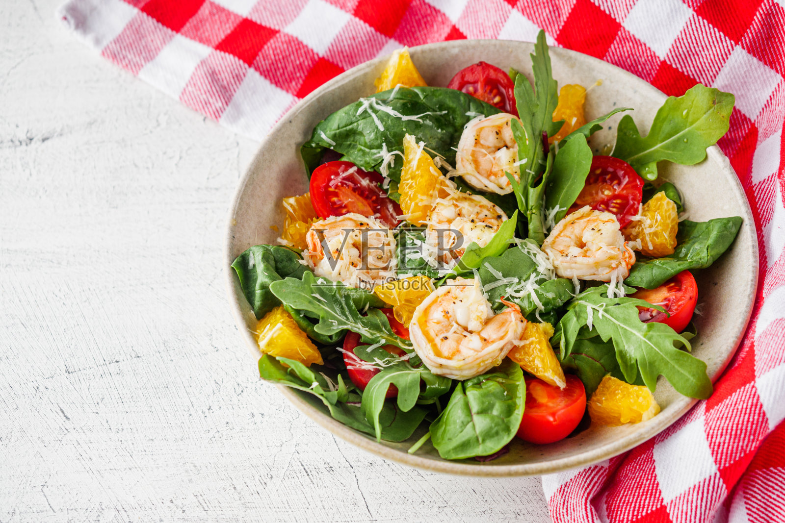 新鲜美味的鲜虾沙拉配橙汁和樱桃番茄，配白色底色照片摄影图片