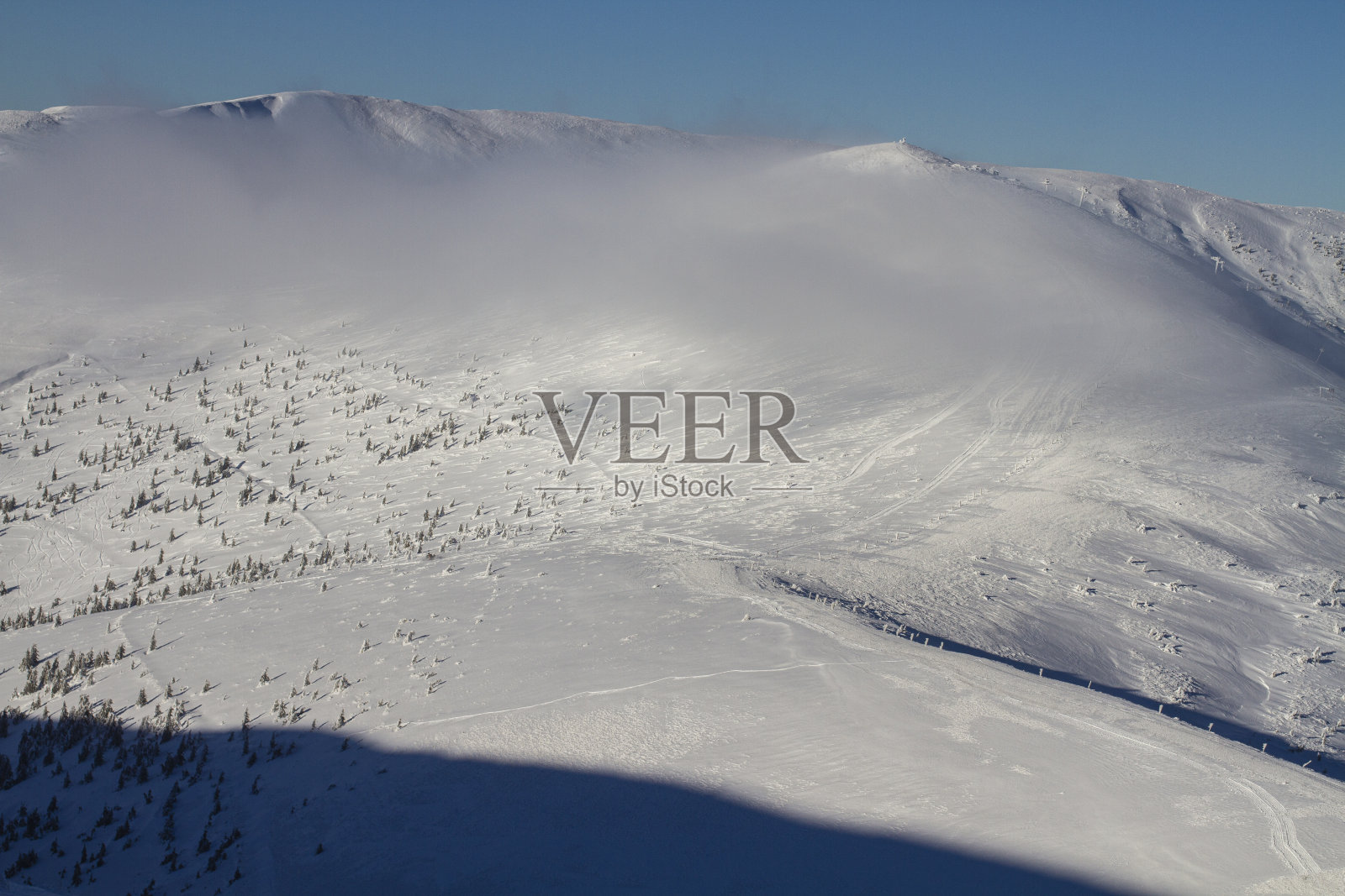 雾覆盖了冬天的山，山上布满了升降机和柱子照片摄影图片