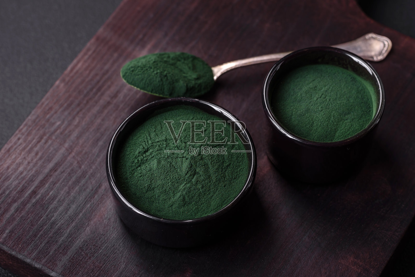 香料，绿色螺旋藻粉的形式在一个黑色的碗照片摄影图片