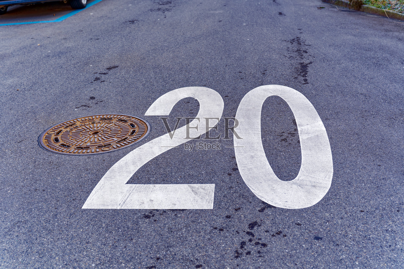Close-up of white road marking speed limit sign 20 kilometers per hour at City of Zürich on a sunny winter day.照片摄影图片