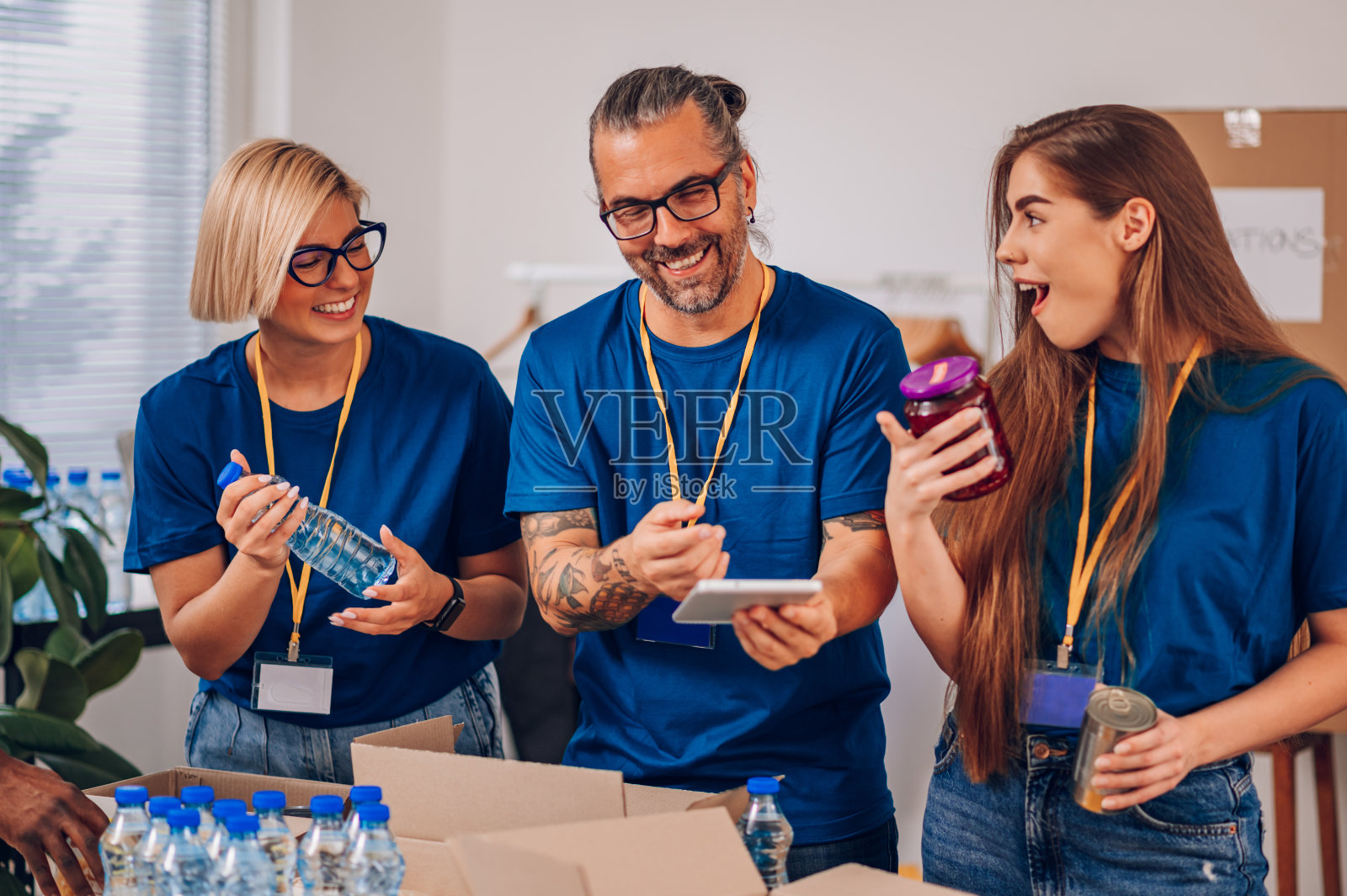 不同的志愿者在慈善捐赠中心工作，打包衣服和食物照片摄影图片