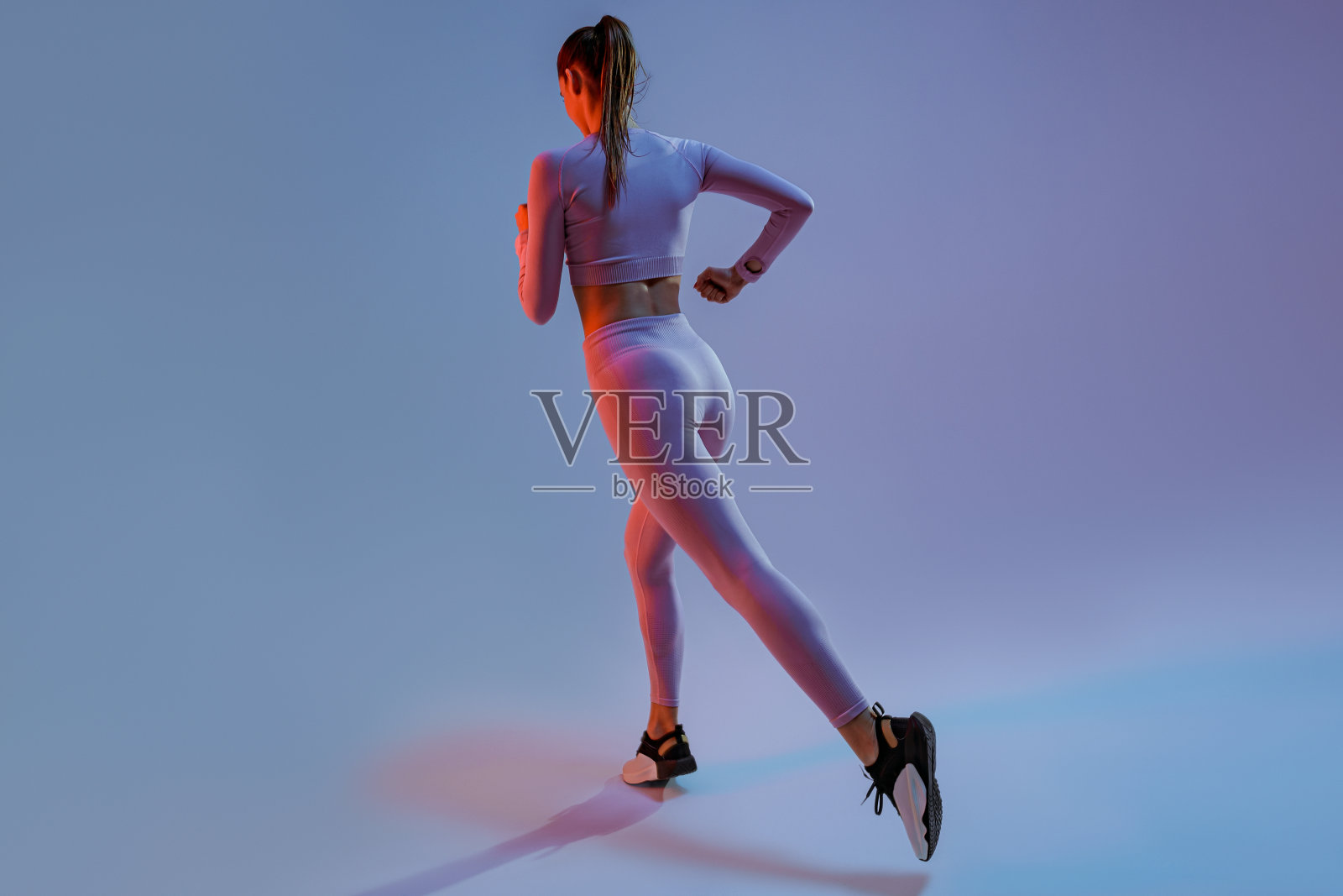 运动的女人跑在半空中锻炼在工作室背景有氧锻炼的背影照片摄影图片