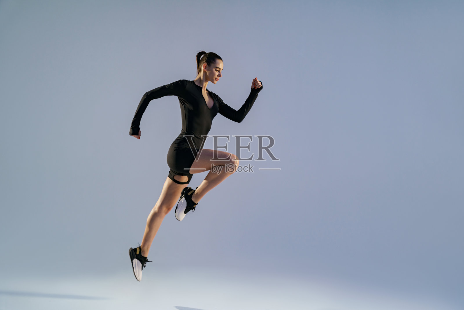 微笑的运动女人在半空中跑步在工作室背景的有氧锻炼照片摄影图片