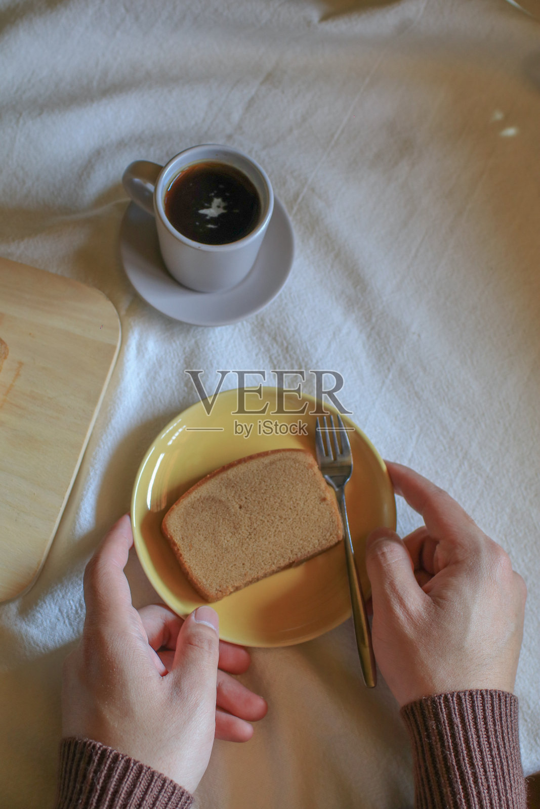 手拿自制黄油面包和咖啡放在白色的桌子上。复古的极简色调。早餐时间。照片摄影图片