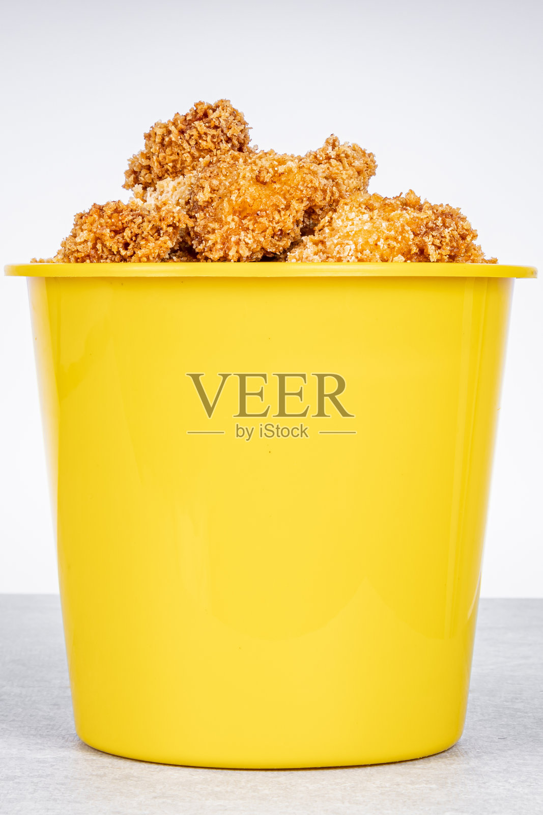 美味的炸鸡放在黄色的桶里，背景是大理石。照片摄影图片