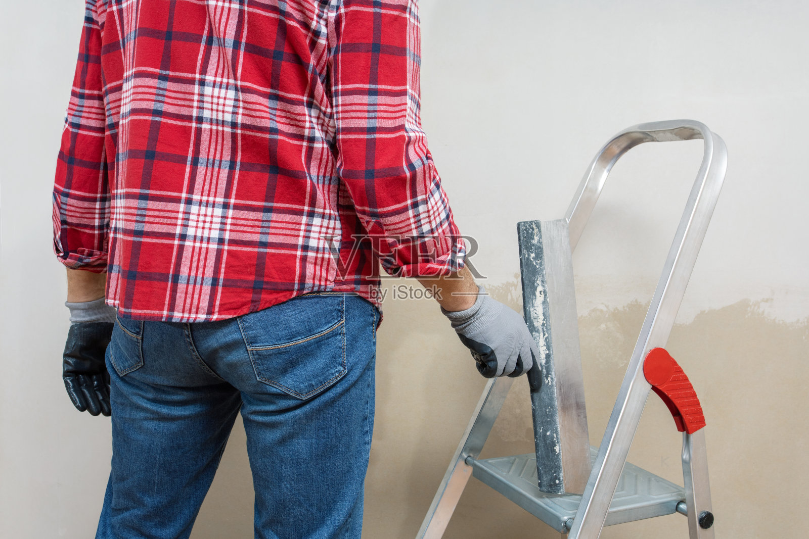 建筑工人正在用抹灰泥把墙壁抹平。照片摄影图片