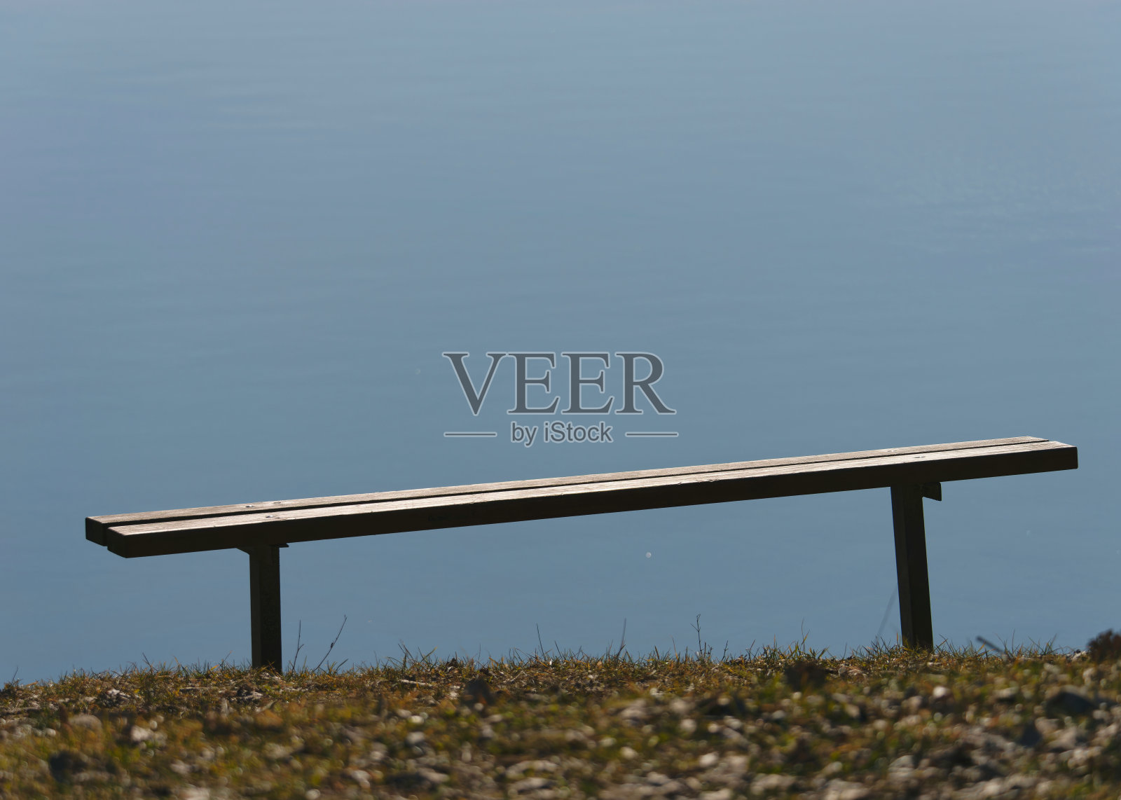 宁静的视野的轮廓，一个阳光明媚的木凳在湖边照片摄影图片