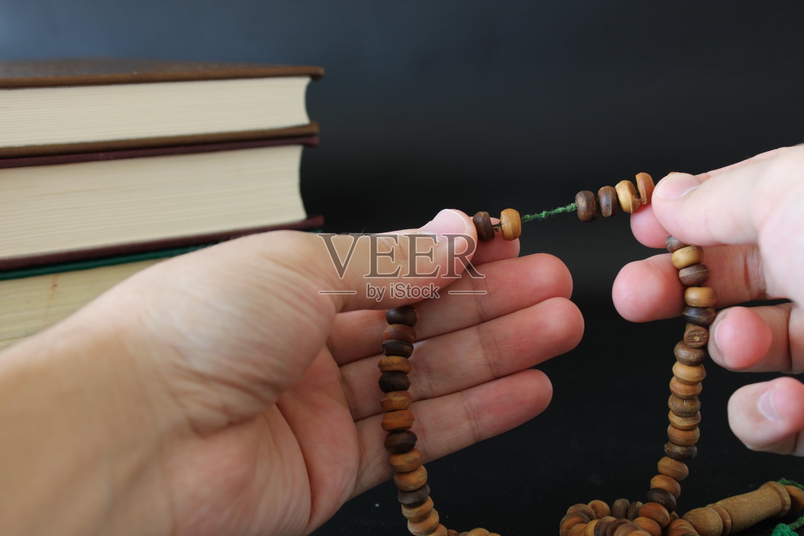 穆斯林用可兰经背景上的念珠祈祷的手照片摄影图片