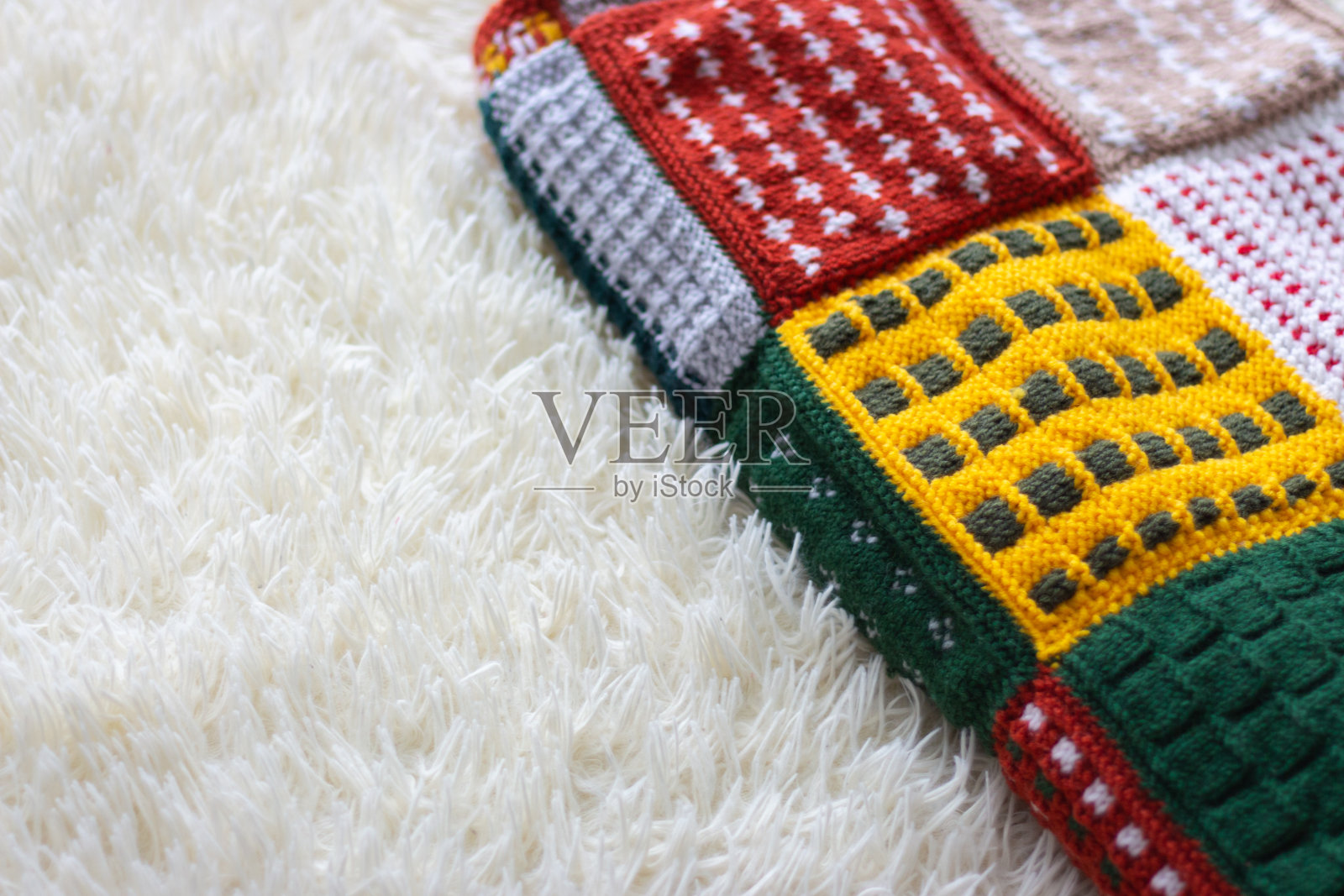 在床上编织温暖的毯子。白色沙发上有毛呢格纹。拼凑而成的格子图案。舒适的房间内部。Hygge风格的卧室。针织的爱好。冬季舒适概念。编织钩针。照片摄影图片