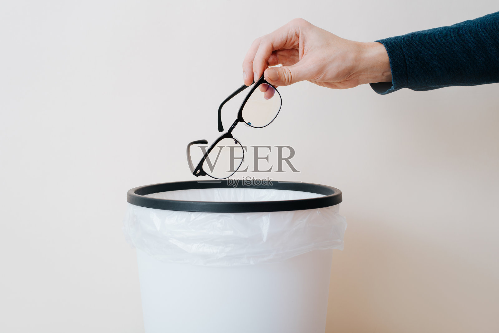 手把眼镜扔进垃圾桶的特写镜头照片摄影图片