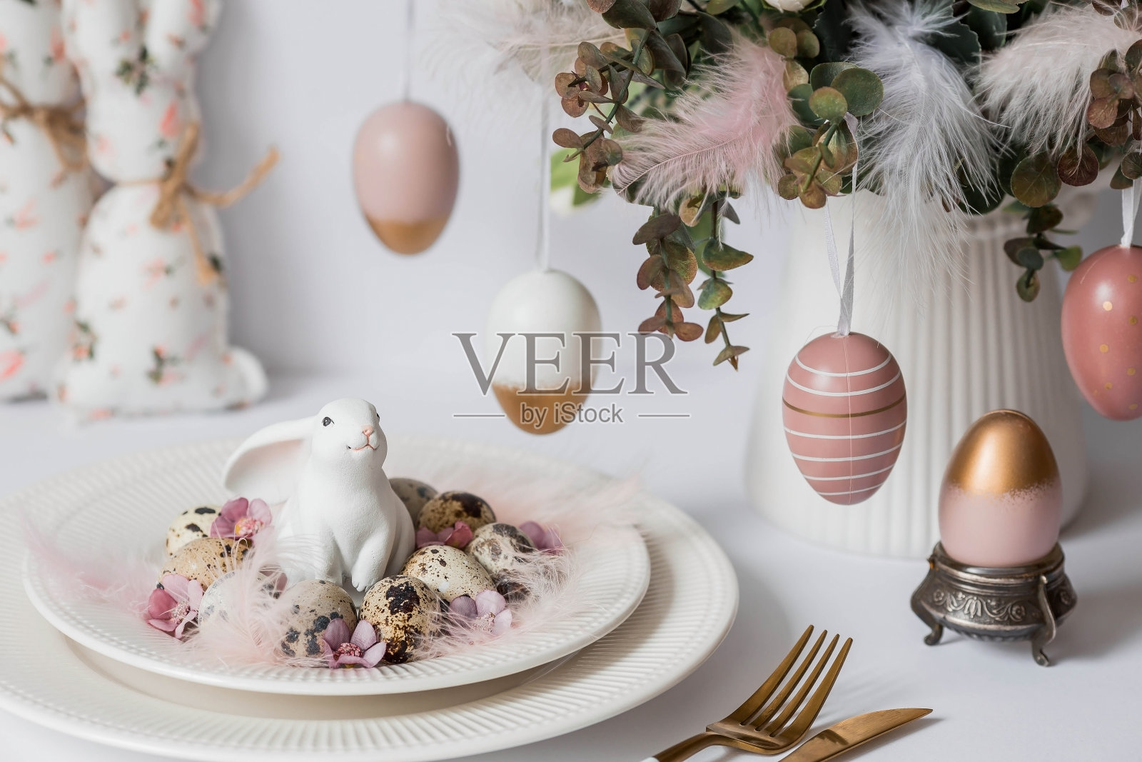 横幅。一个明亮的复活节假期的概念。一束有羽毛、白兔和复活节彩蛋的花，盘子里的白色背景。漂亮的复活节卡片。照片摄影图片