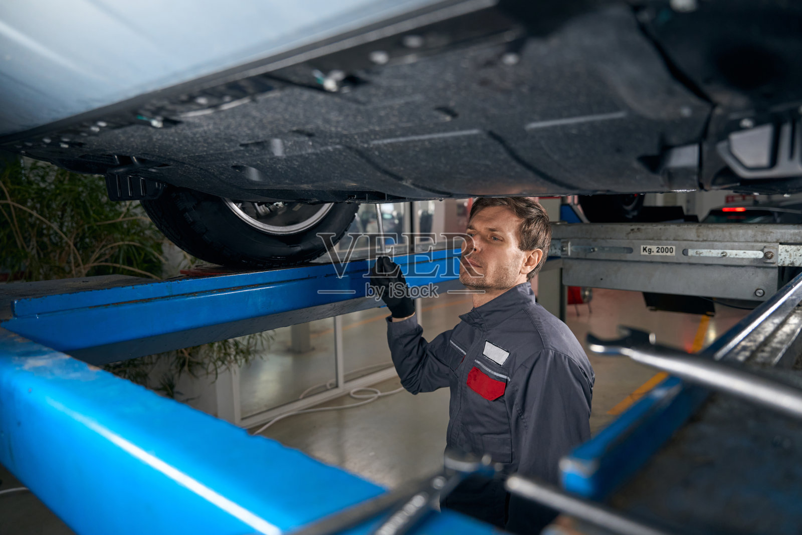 维修人员在车间检查汽车下的车轮照片摄影图片