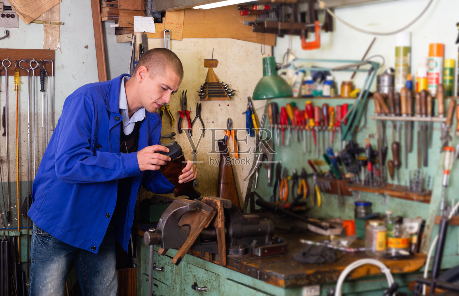 枪匠在武器车间修理霰弹枪的枪托照片摄影图片