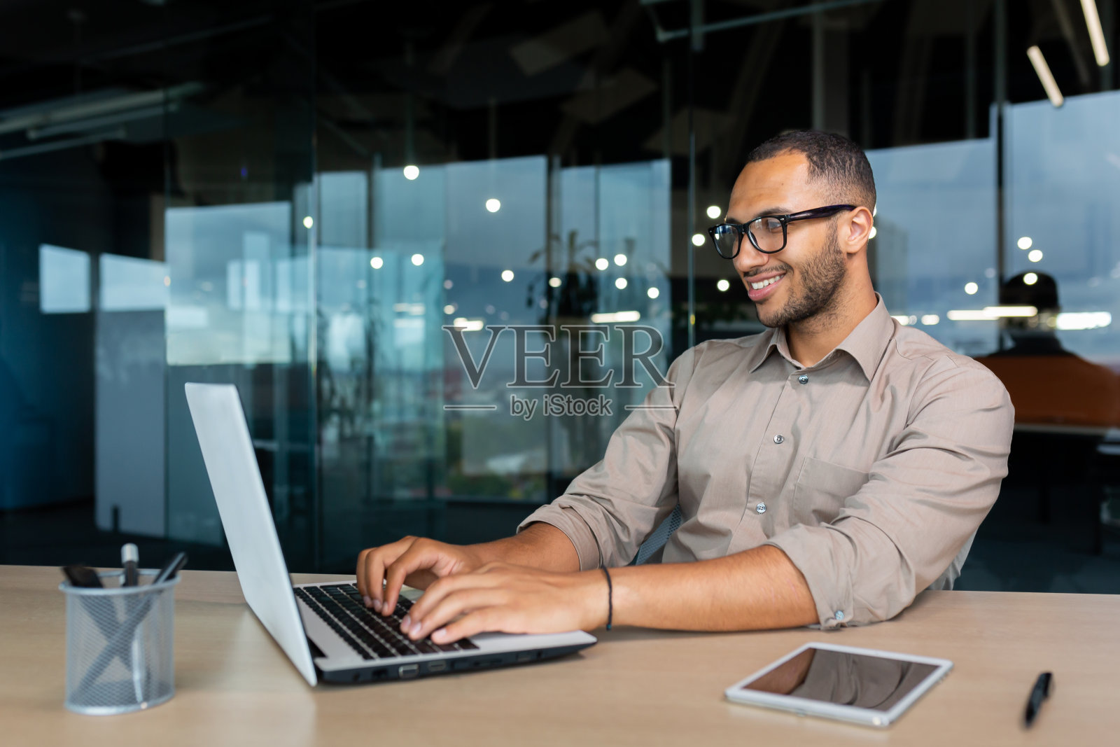 年轻成功的印度程序员在现代开发公司工作，男人用笔记本电脑写软件代码照片摄影图片