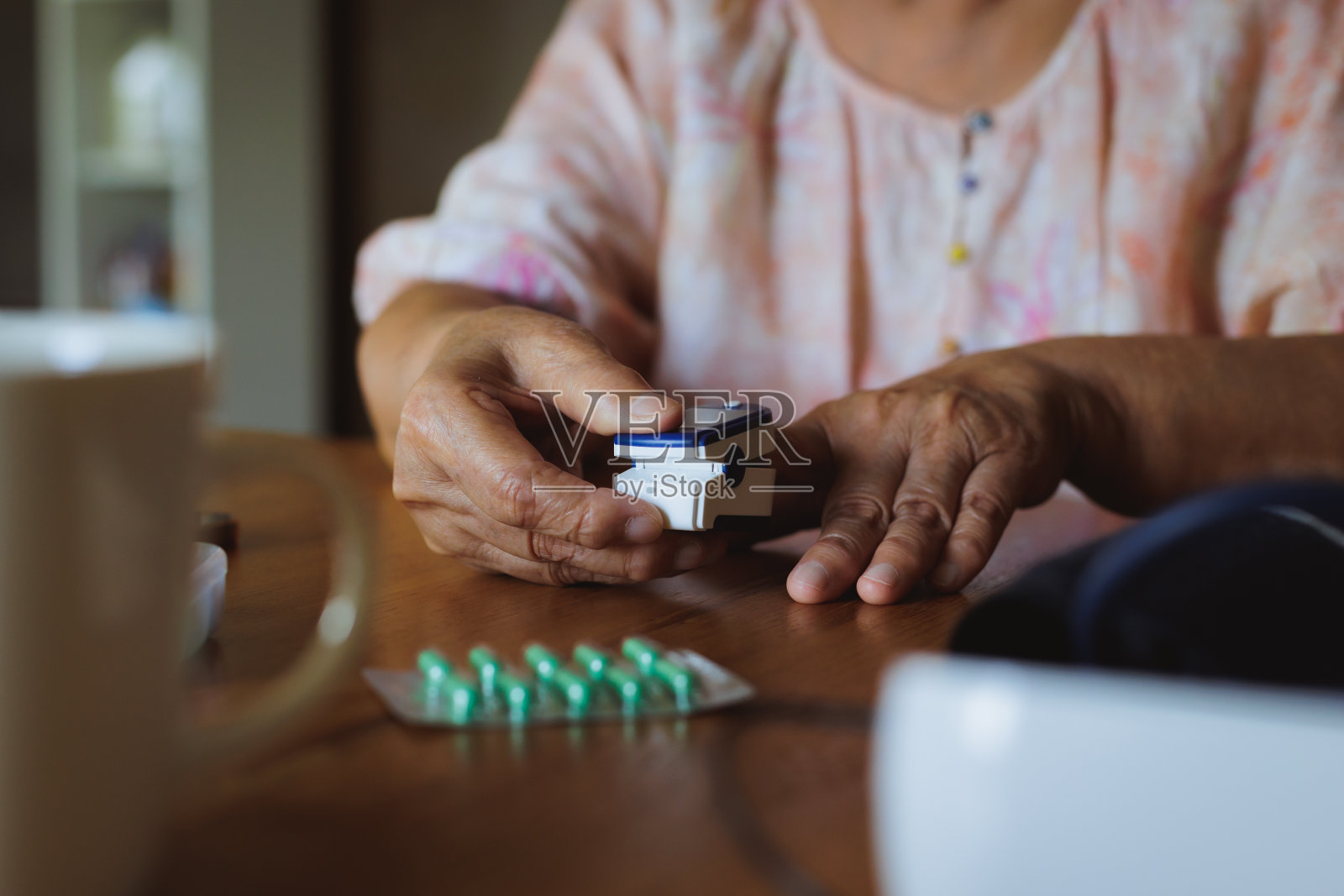 高级亚洲妇女自我测试血氧水平从脉搏血氧计在她的手指在家里。照片摄影图片
