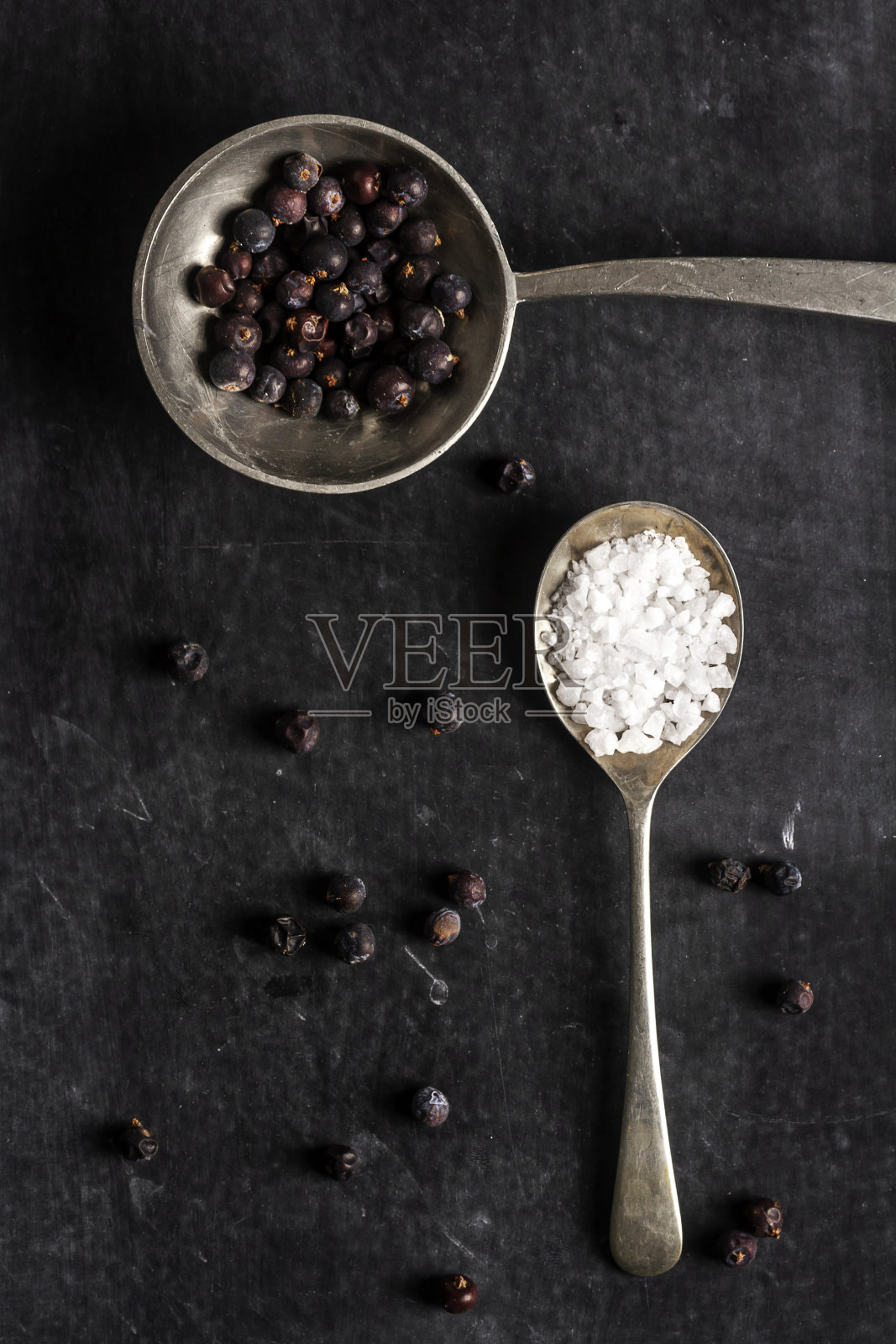 两把旧勺子，黑色背景上有杜松子和盐照片摄影图片