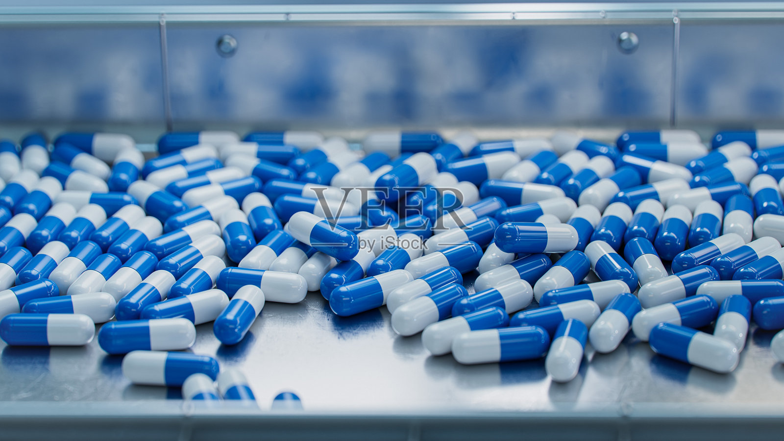 现代制药厂传送带上的蓝色胶囊。片剂和胶囊制造工艺。医用药品生产线。照片摄影图片