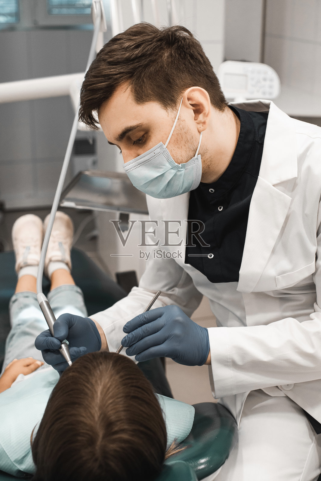 医学、口腔医学及保健理念。专业的年轻男性牙医与小女孩在诊所工作。照片摄影图片