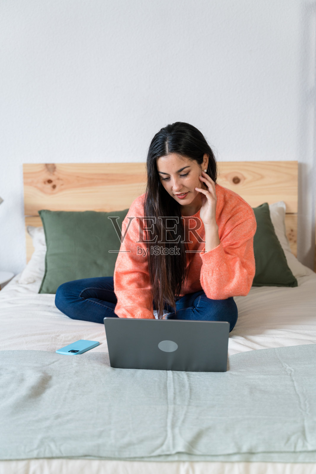 微笑的女人在床上使用笔记本电脑照片摄影图片