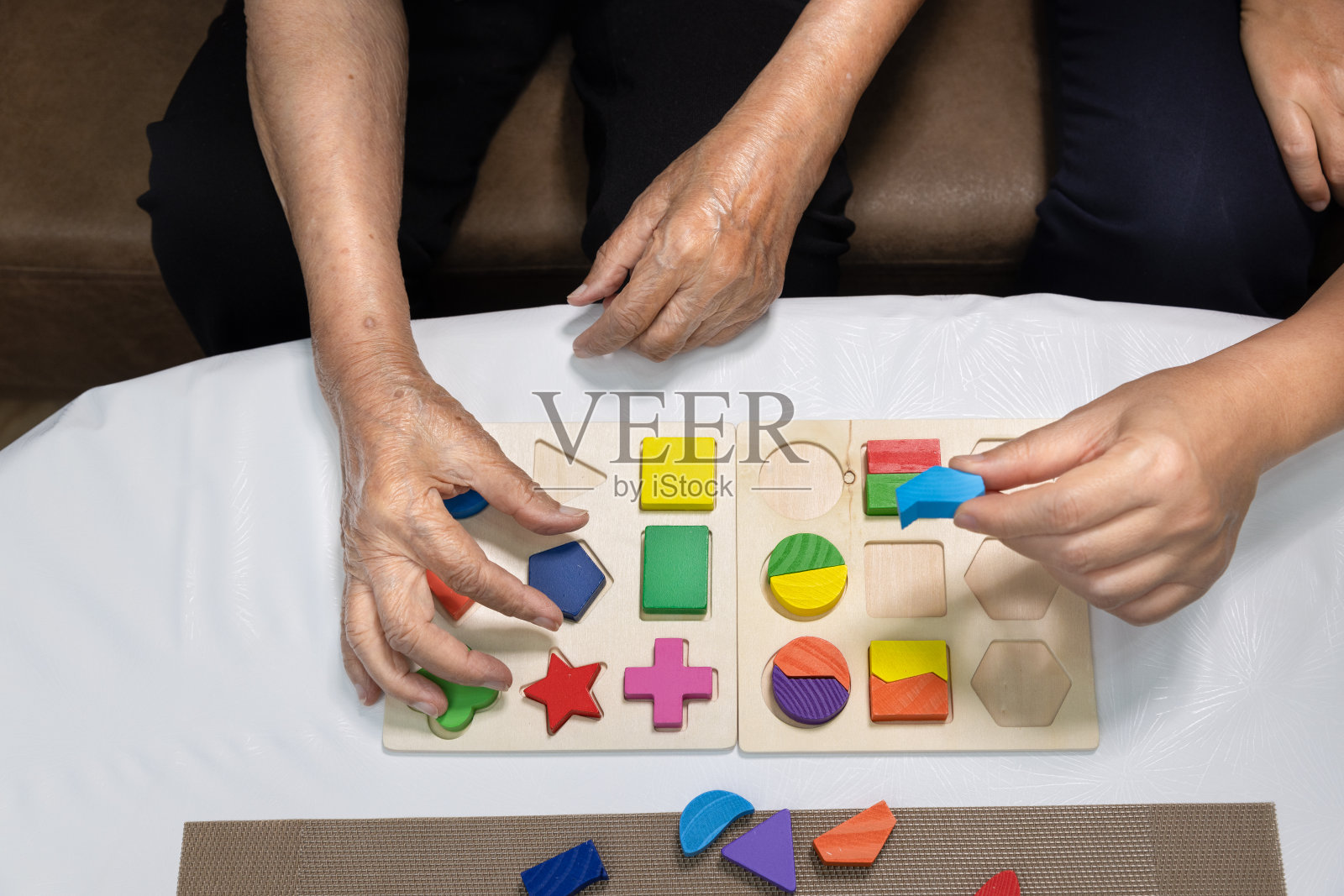 护理人员和老年妇女玩木形拼图游戏预防痴呆症照片摄影图片