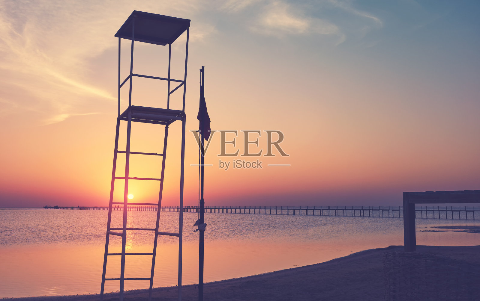 救生员塔剪影在日落的热带海滩，颜色照片摄影图片