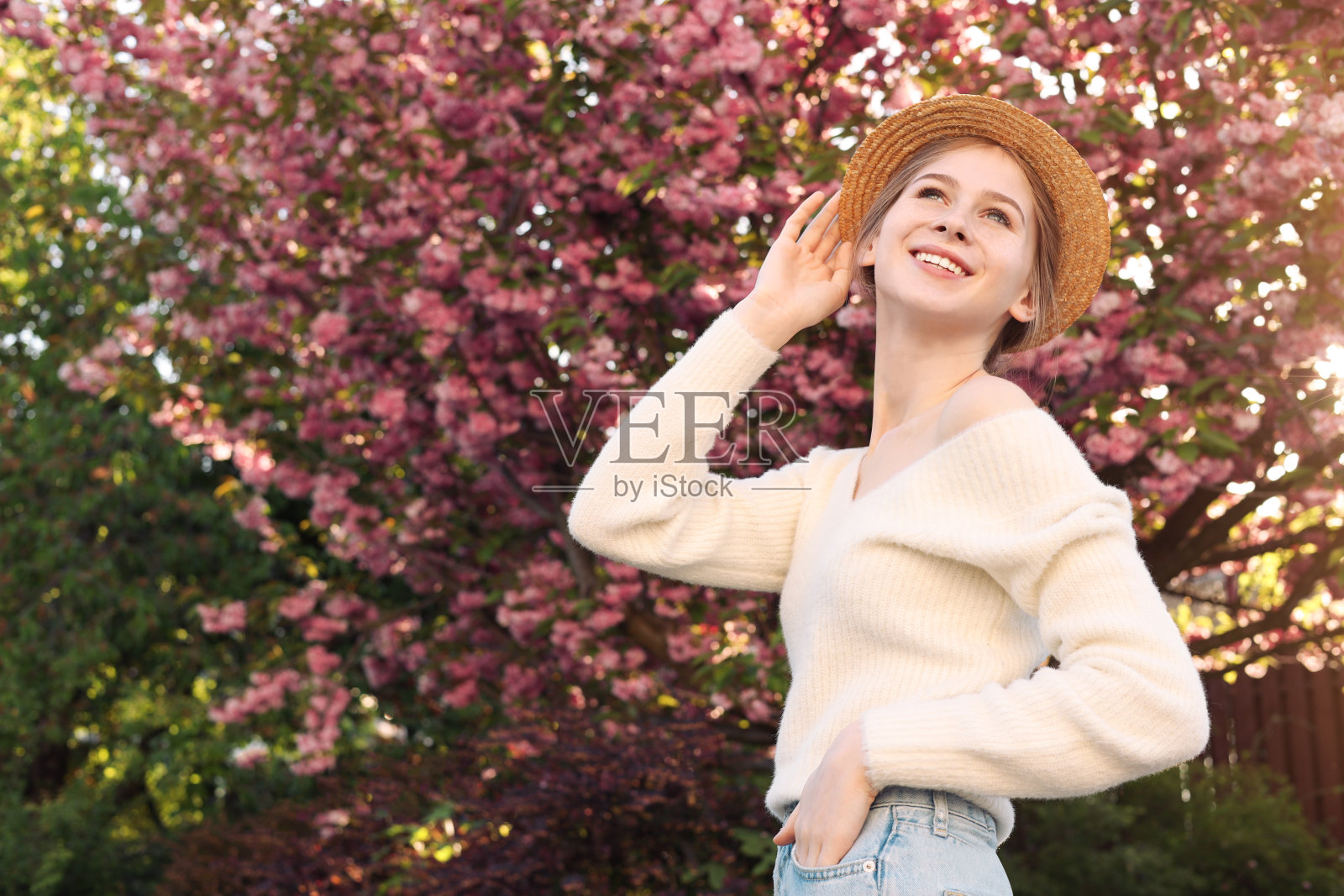 戴帽少女在春日开花的树旁照片摄影图片