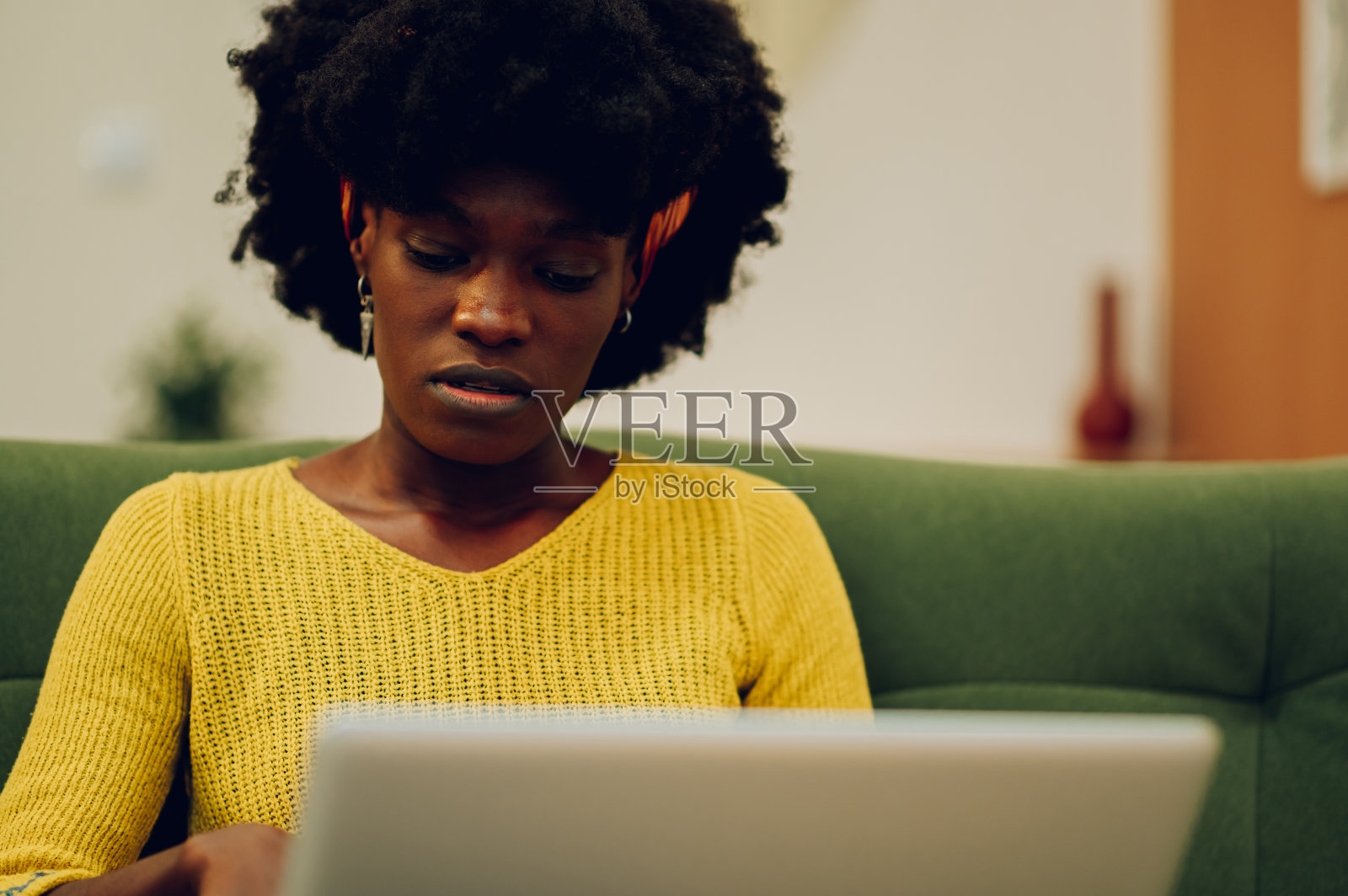 压力大的非裔美国妇女坐在家里的沙发上使用笔记本电脑照片摄影图片