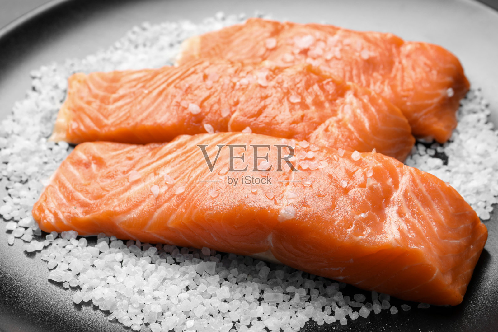 新鲜生三文鱼加盐，黑色盘子，特写照片摄影图片