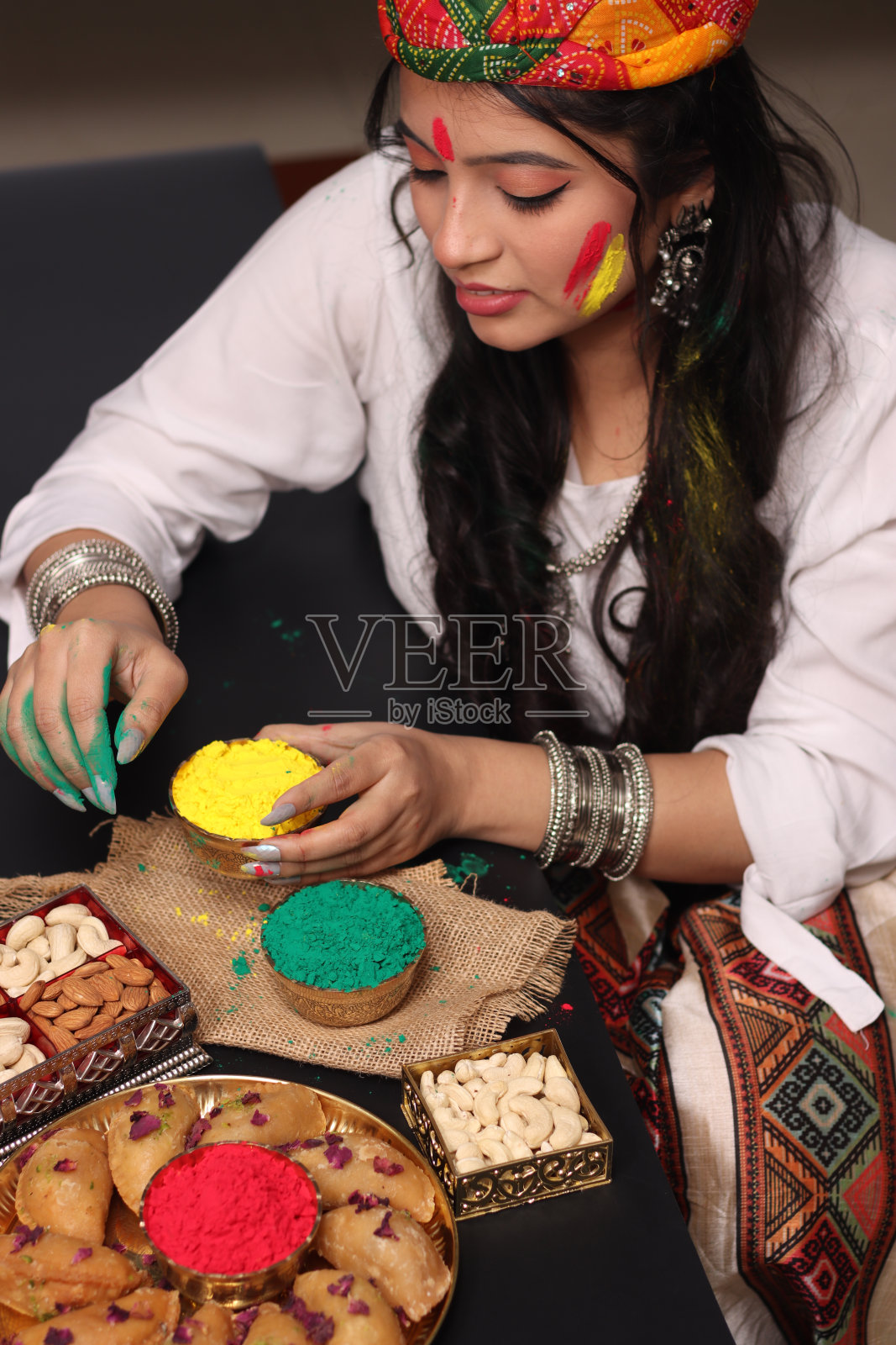 一个美丽的女人女孩女士在一个位置安排Abeer gulal干色粉和印度甜Gujiya pedukiya kashew为庆祝胡里节的颜色照片摄影图片