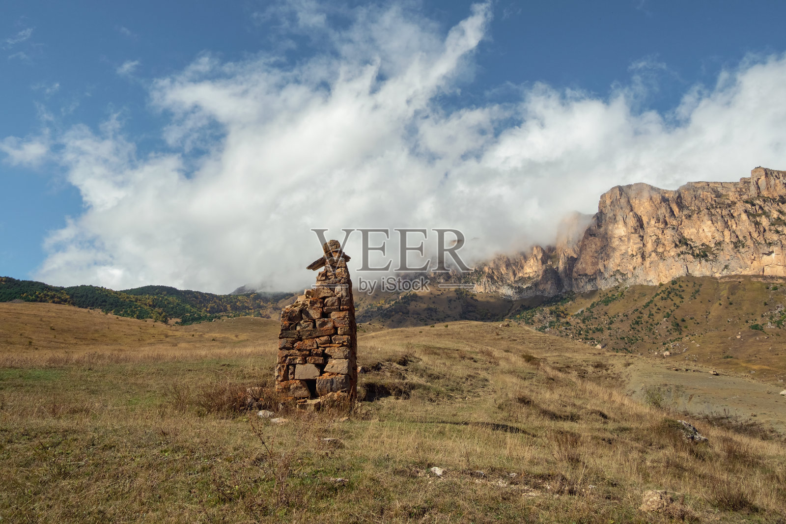 一尊古老的石像，背景是雾气缭绕的群山。石头做的墓碑。Stur-Digora地区。北奥塞梯。照片摄影图片