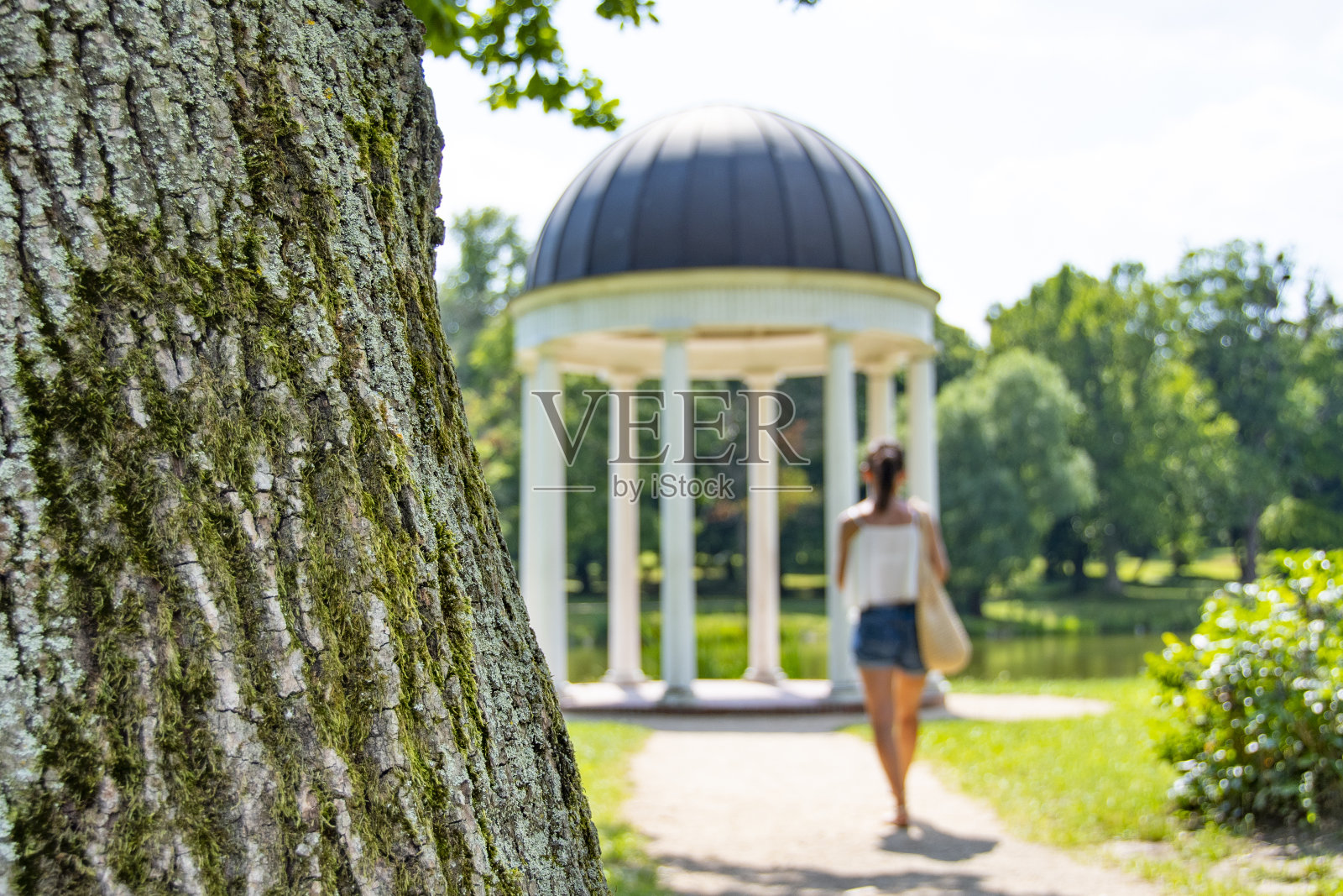 湖边公园里有亭子，一个女人在夏日的阳光下照片摄影图片