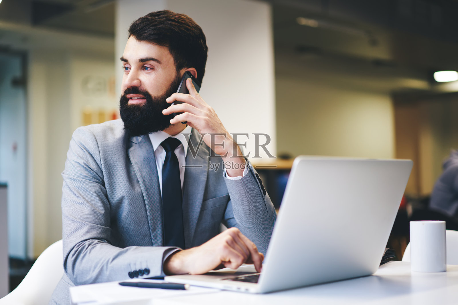 积极的商人在工作时用智能手机讲话照片摄影图片