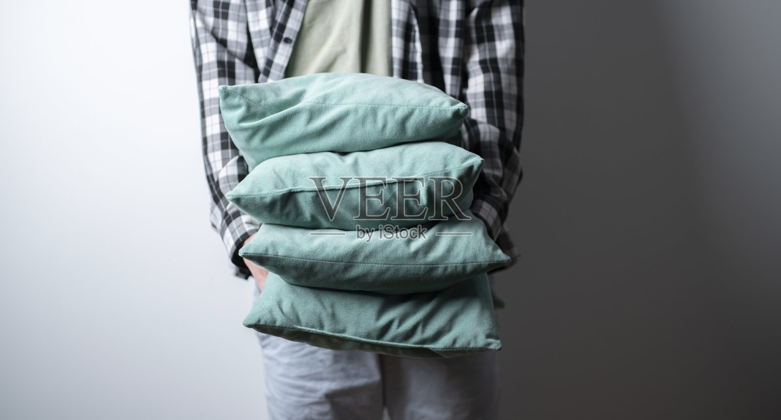 抱着一堆干净的灰色枕头的人照片摄影图片